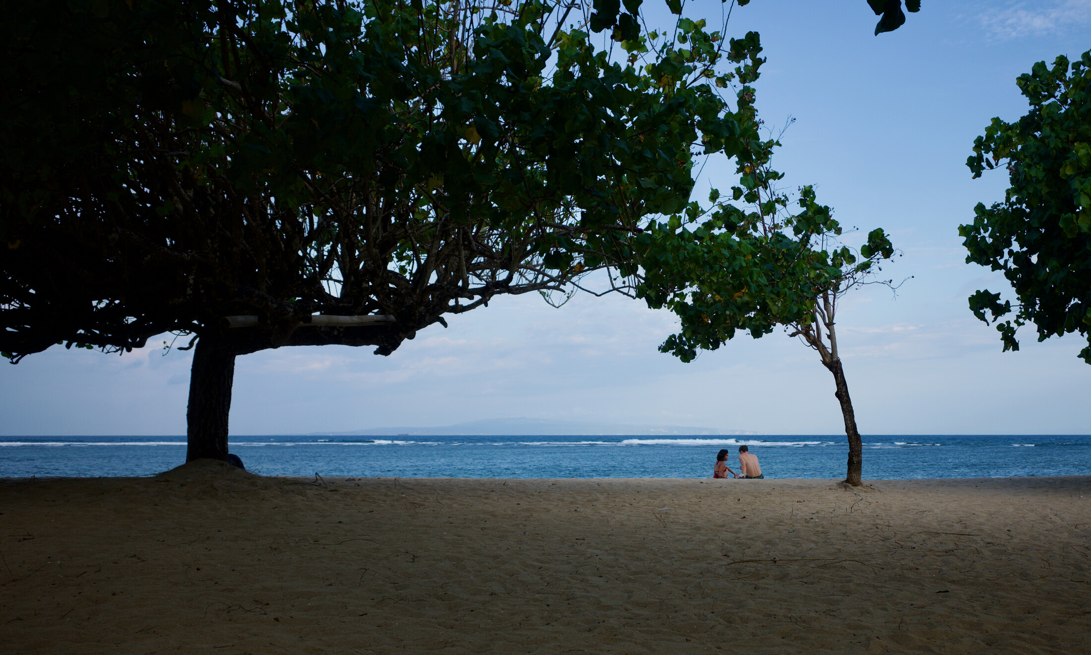 A couple sitting on Sanur beach just before sunset