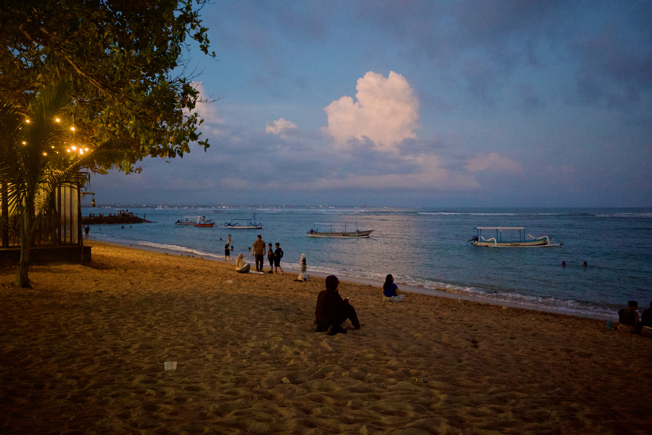 Some Balinese locals sitting on the beach around sunset